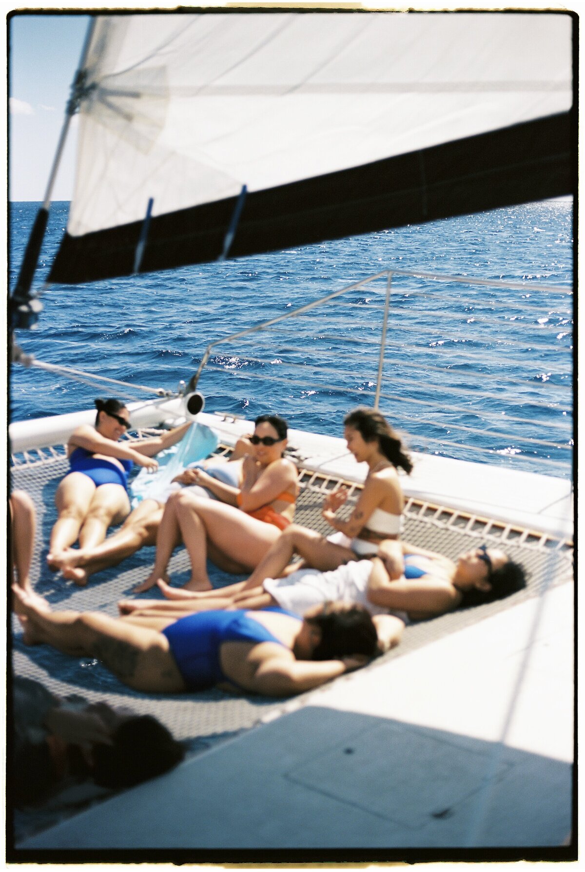 Engagement party on a catamaran sailing boat, captured on film by Kate Winters Photography, showcasing authentic moments in a documentary style.