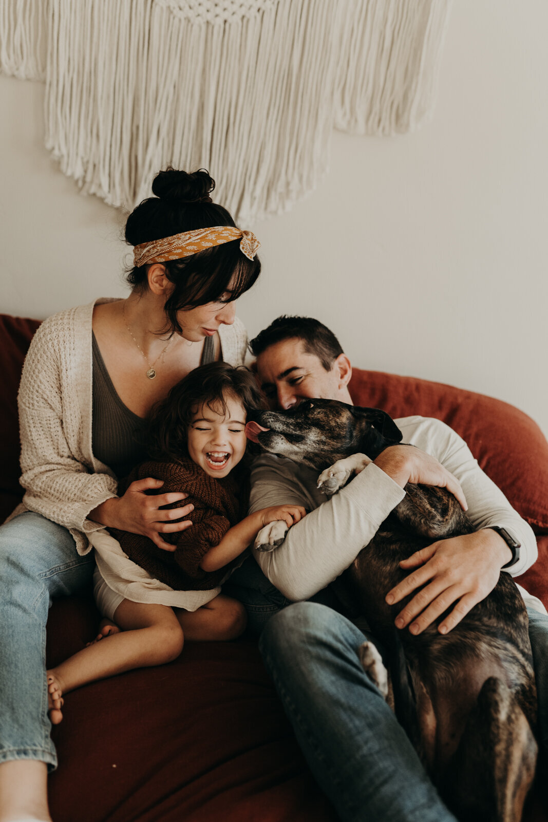 family and dog sitting on bed