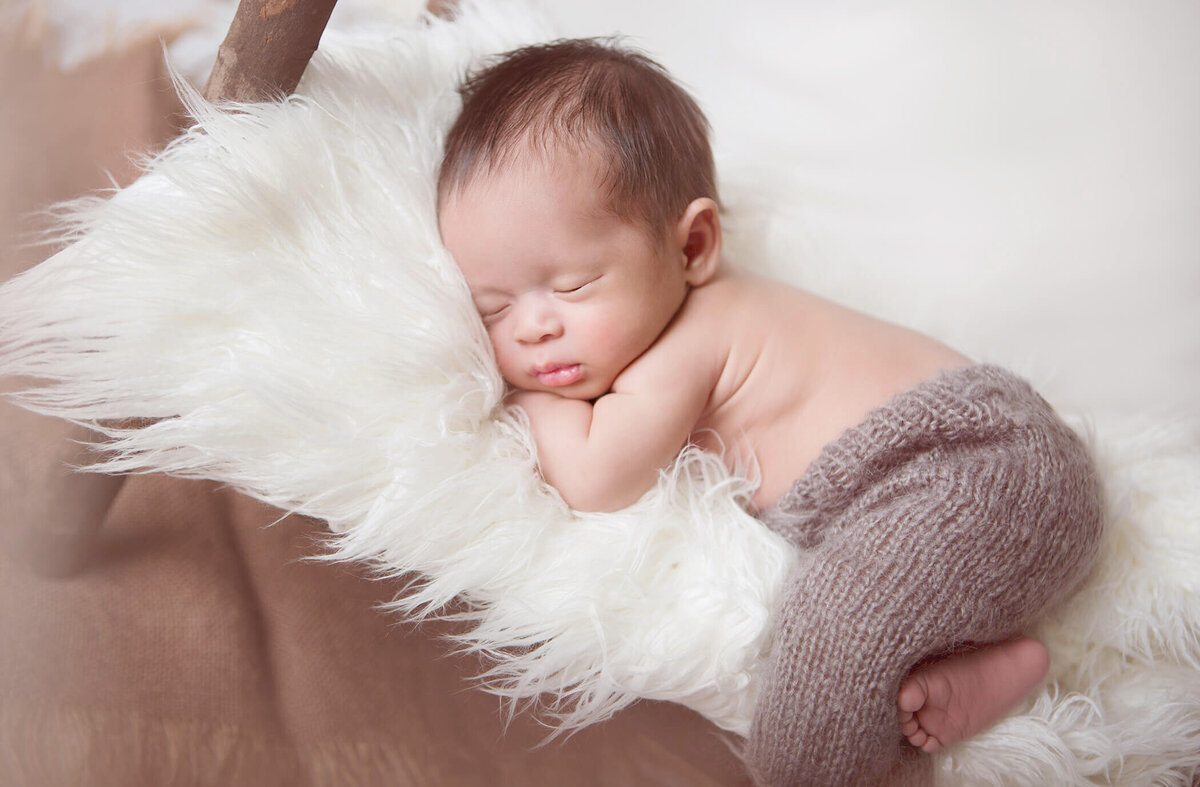 Newborn baby asleep on a newborn sized bed at Los Angeles newborn photoshoot
