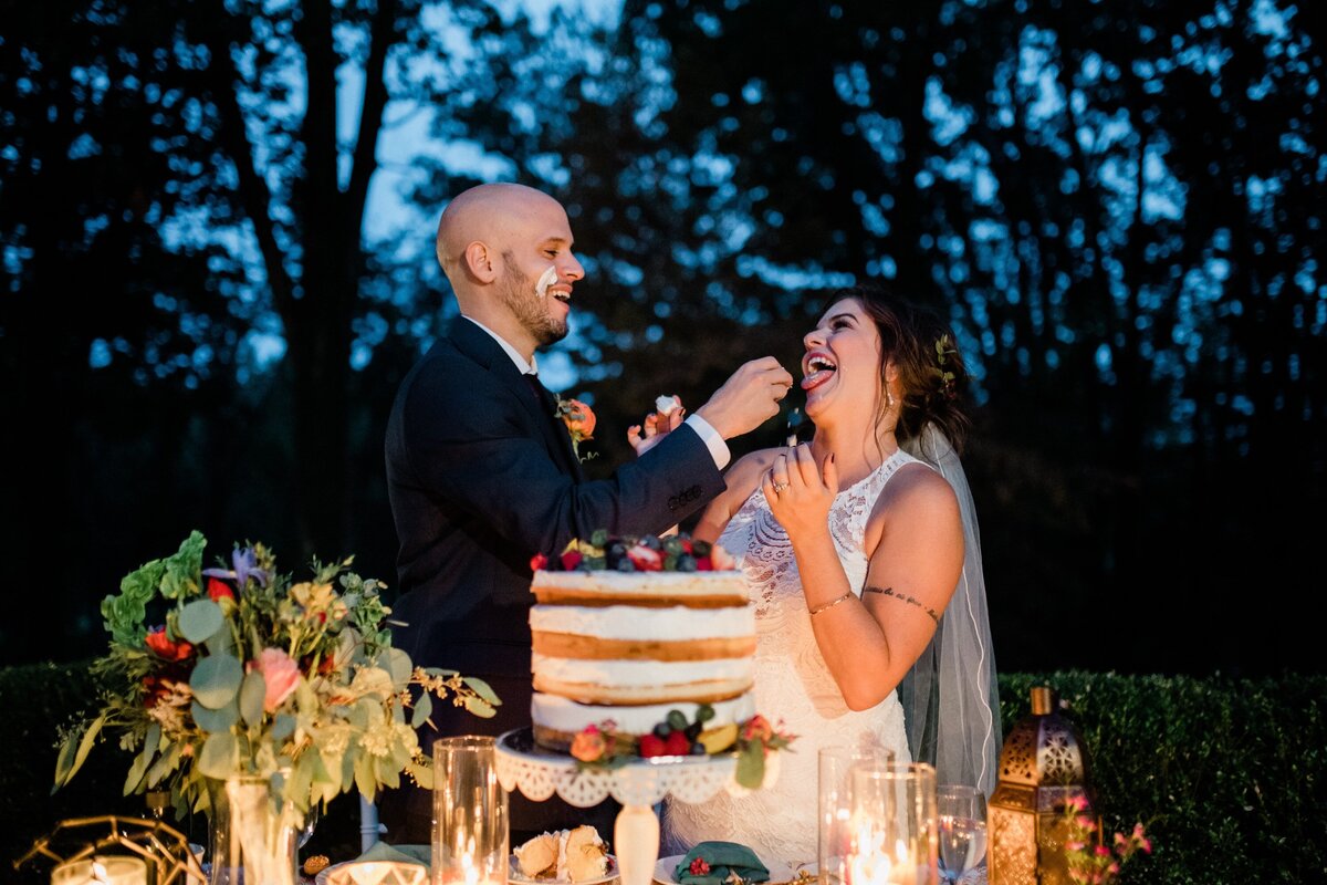Bride and groom eating their cake at dusk in a backyard wedding in Harrisburg