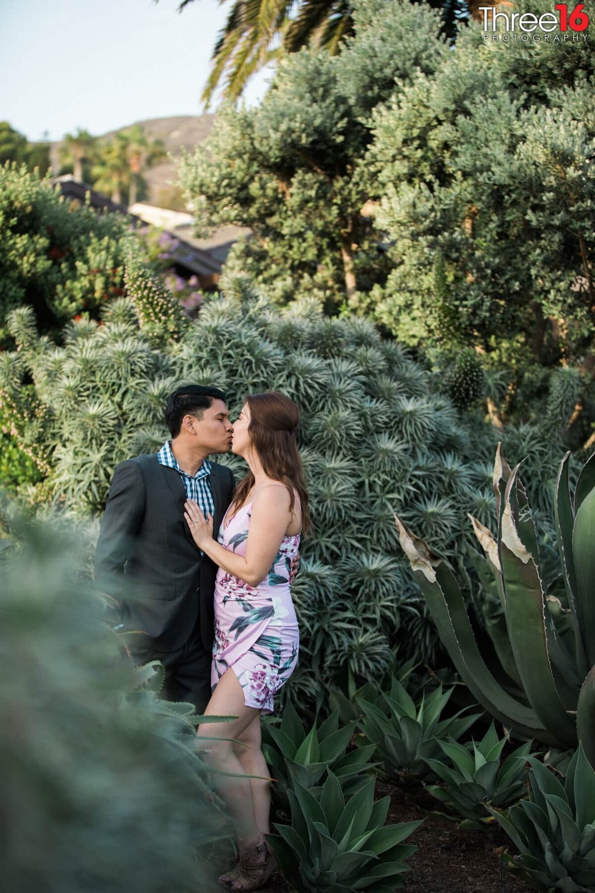 Newly engaged couple share a tender kiss amongst the greenery at The Montage after a marriage proposal
