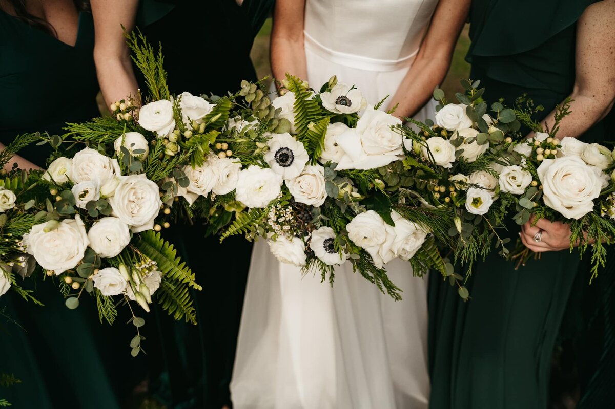 bouquets featuring white roses, white anemone, winter greenery loose and lush