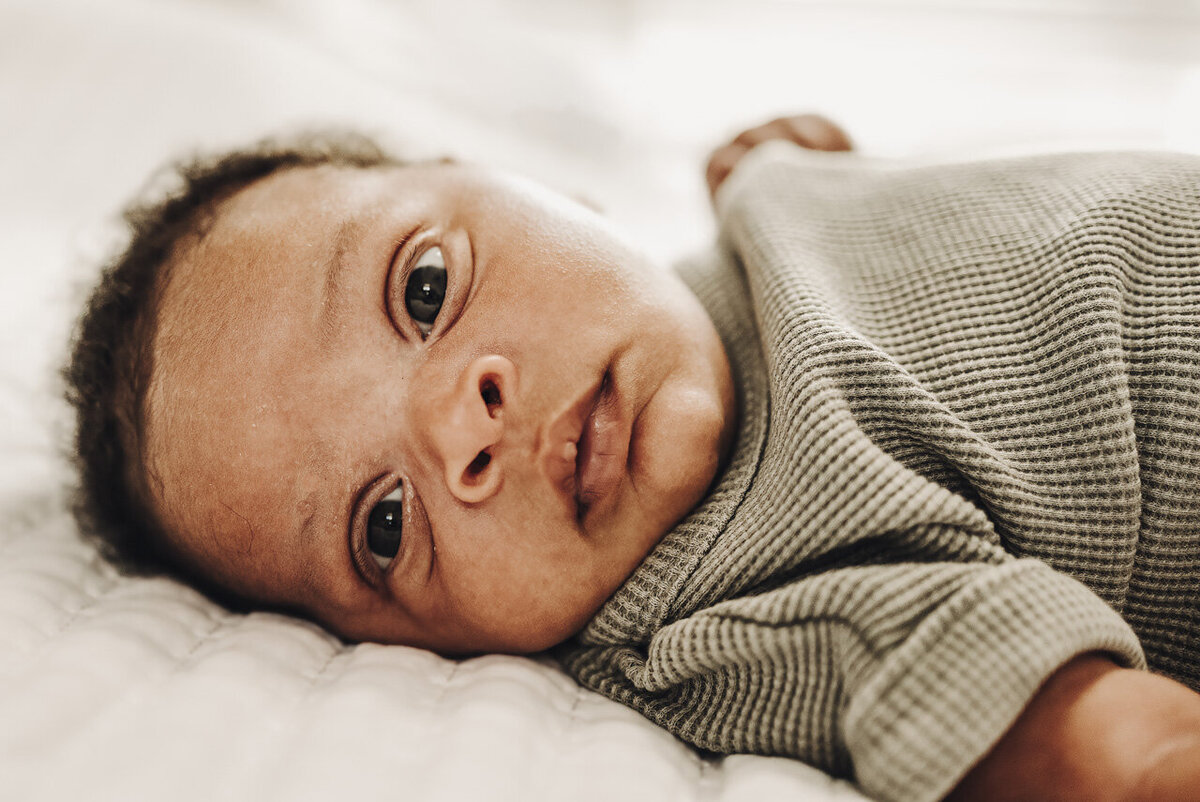 Newborn baby looks directly into camera by lifestyle and newborn photographer in Tifton, Georgia