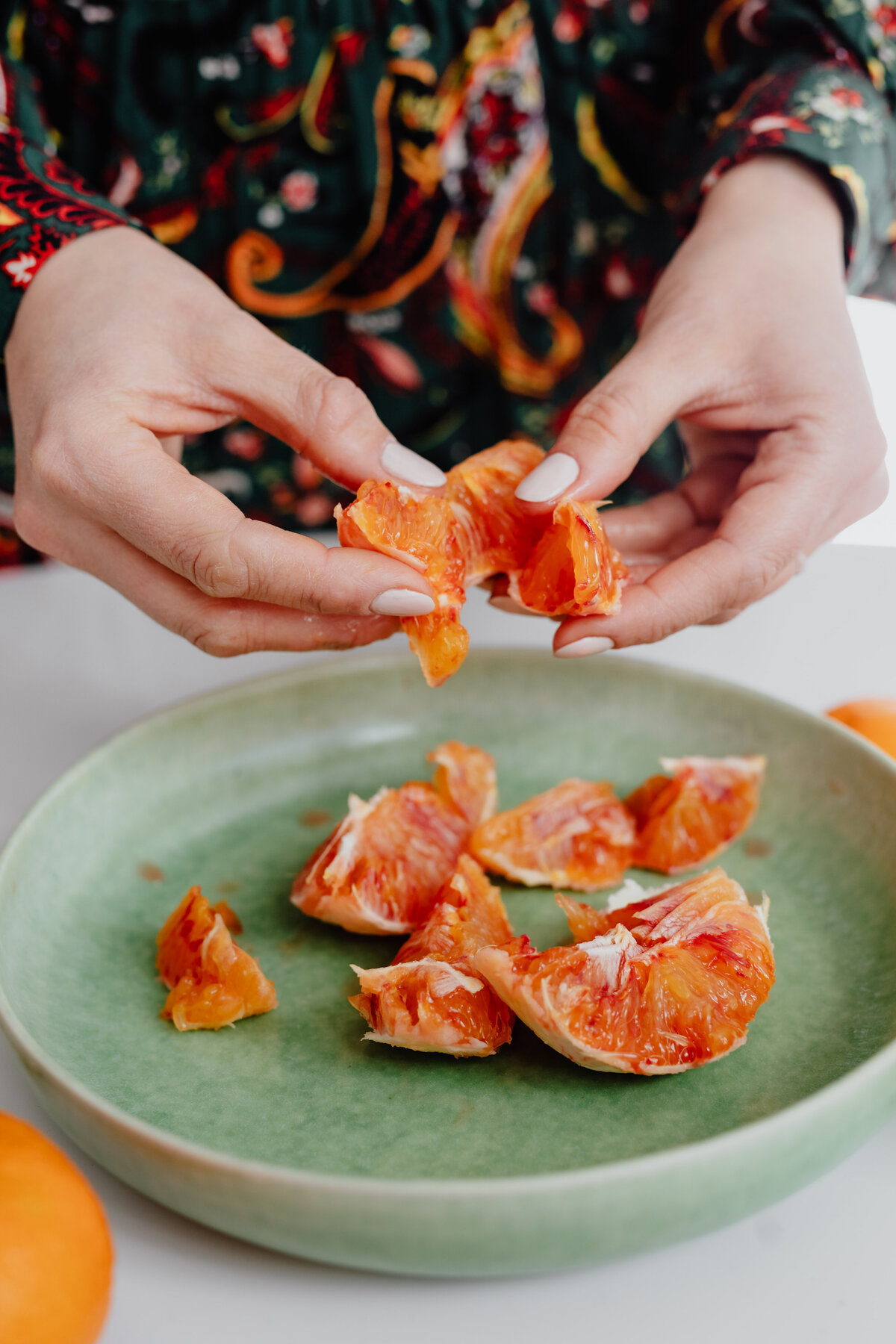 kaboompics_a-woman-peels-an-orange-on-a-green-plate-13277