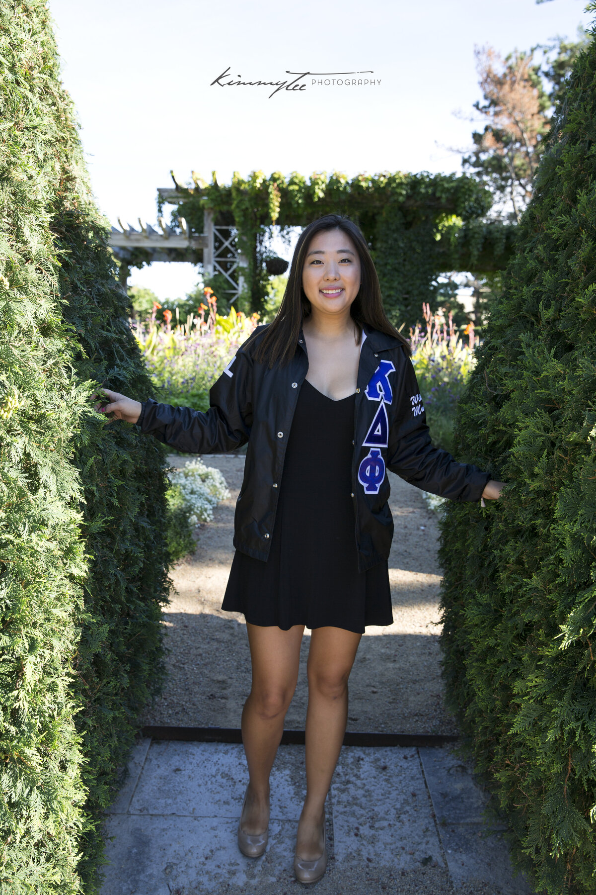 Smiling girl in sorority jacket between two hedges