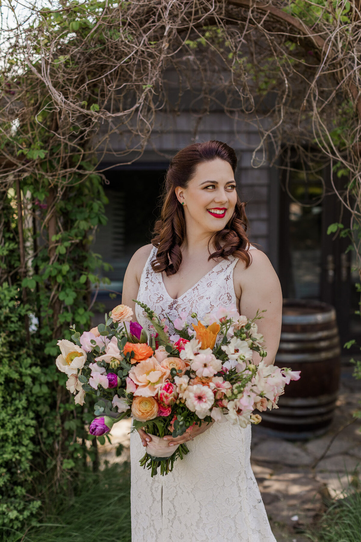 Bride-looks-down-at-her-colorful-bouquet-of-flowers-at-her-wedding-at-venue-Hidden-Meadows-in-Snohomish-WA-photo-by-Joanna-Monger-Photography