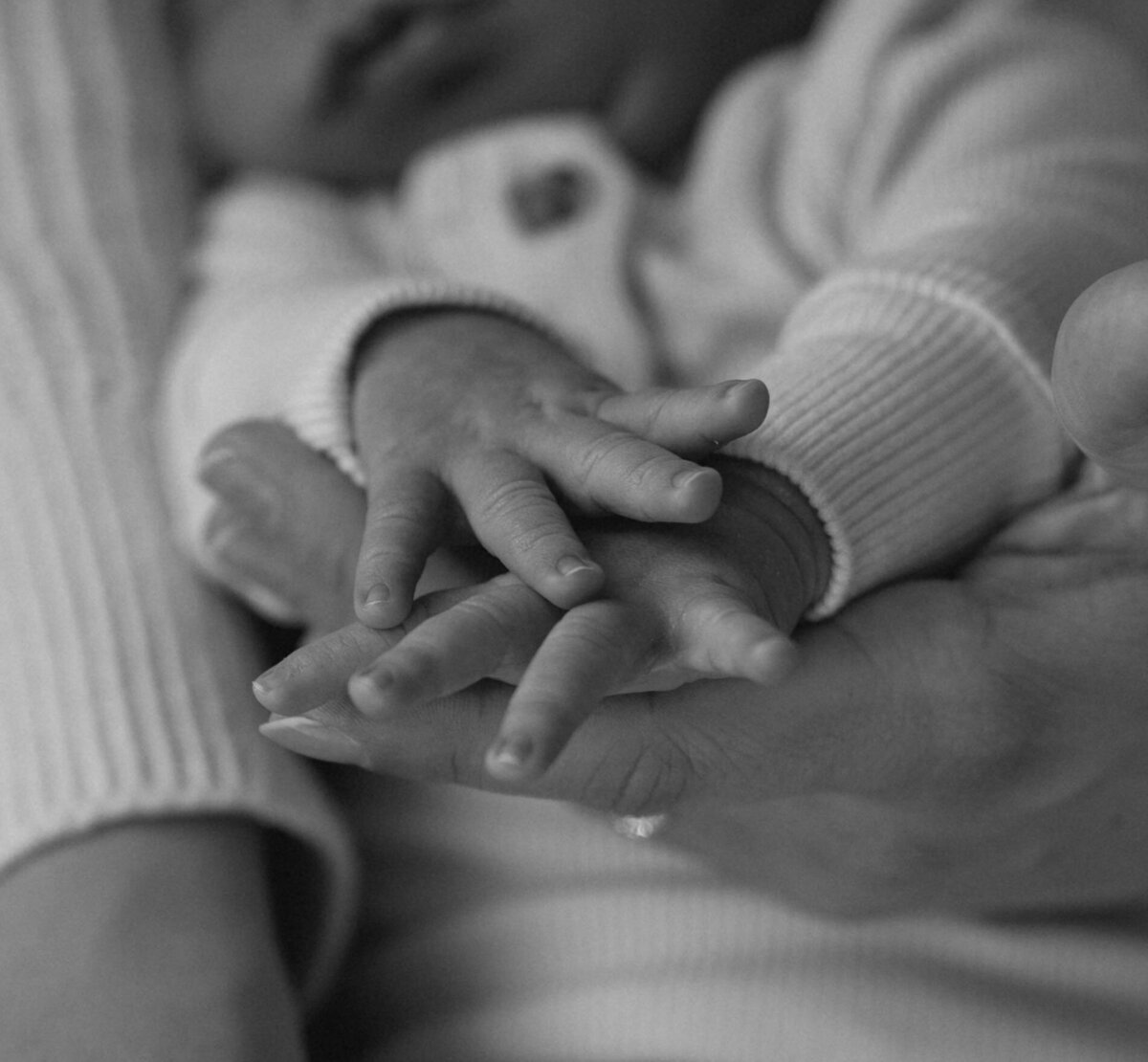 close up of mother's hands holding newborn baby's hands