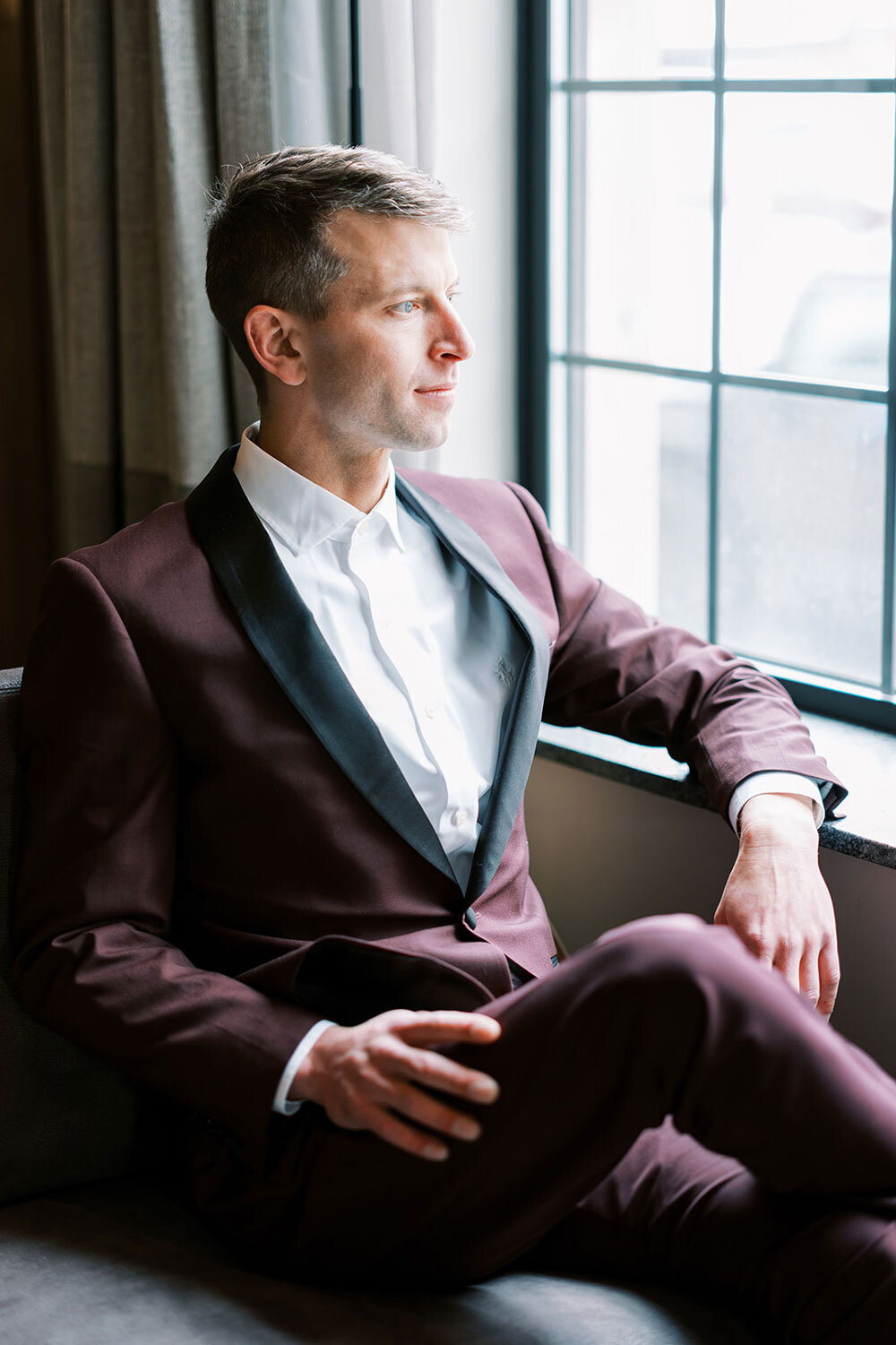 Groom in a burgundy tuxedo with black lapels at the Kimpton Armory Hotel, during a modern wedding inspiration shoot in Bozeman, Montana.