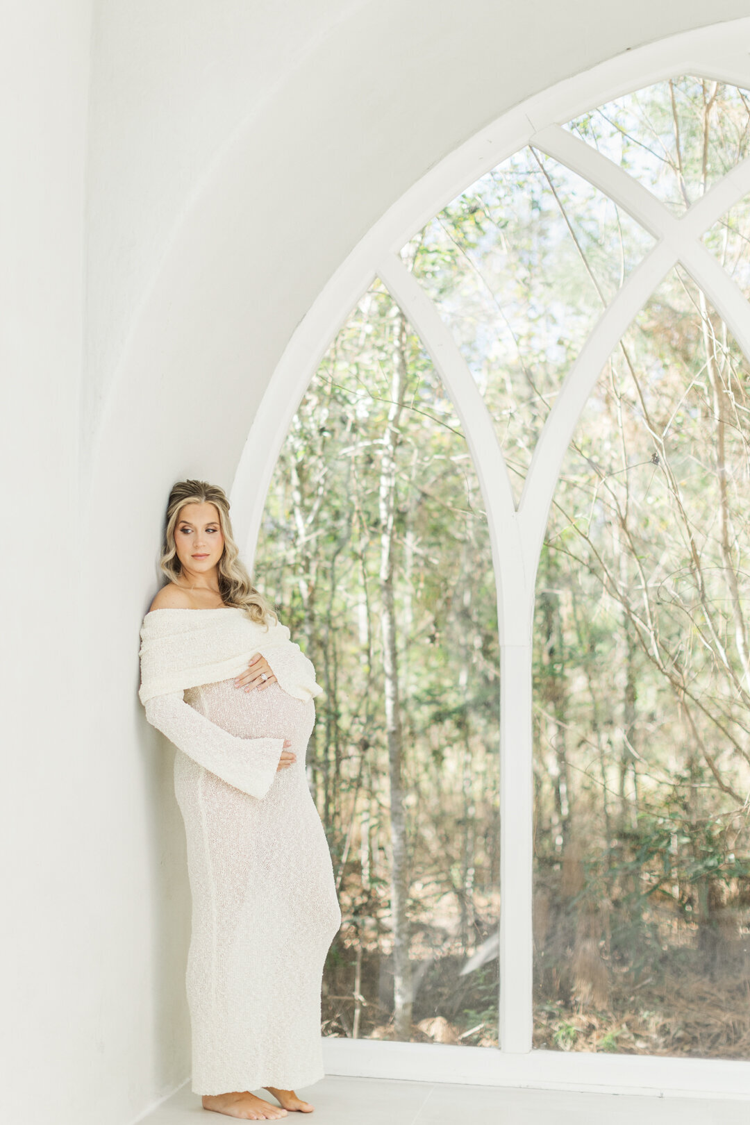 pregnant mom holds belly glancing off into the distance at houston studio