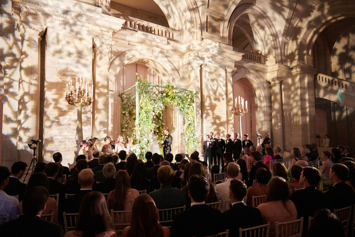 The grand wedding ceremony at The New York Public Library in New York City was captured beautifully in a photo by photographer Shawn Connell. Additionally, videographers Aaron Navak Films documented the special moments of the day, adding a cinematic touch to the event.