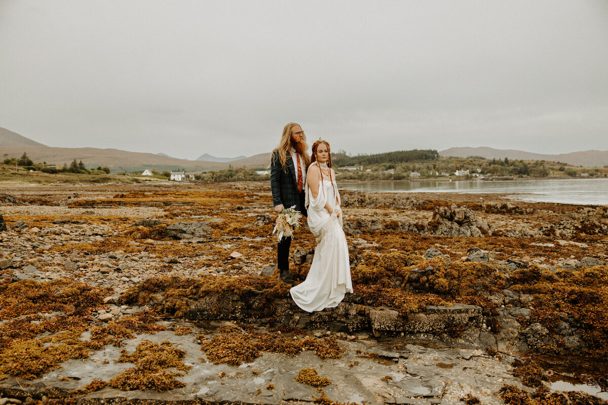 Adventure elopement couple holding hands on a cliff in Isle of Skye Scotland during golden hour