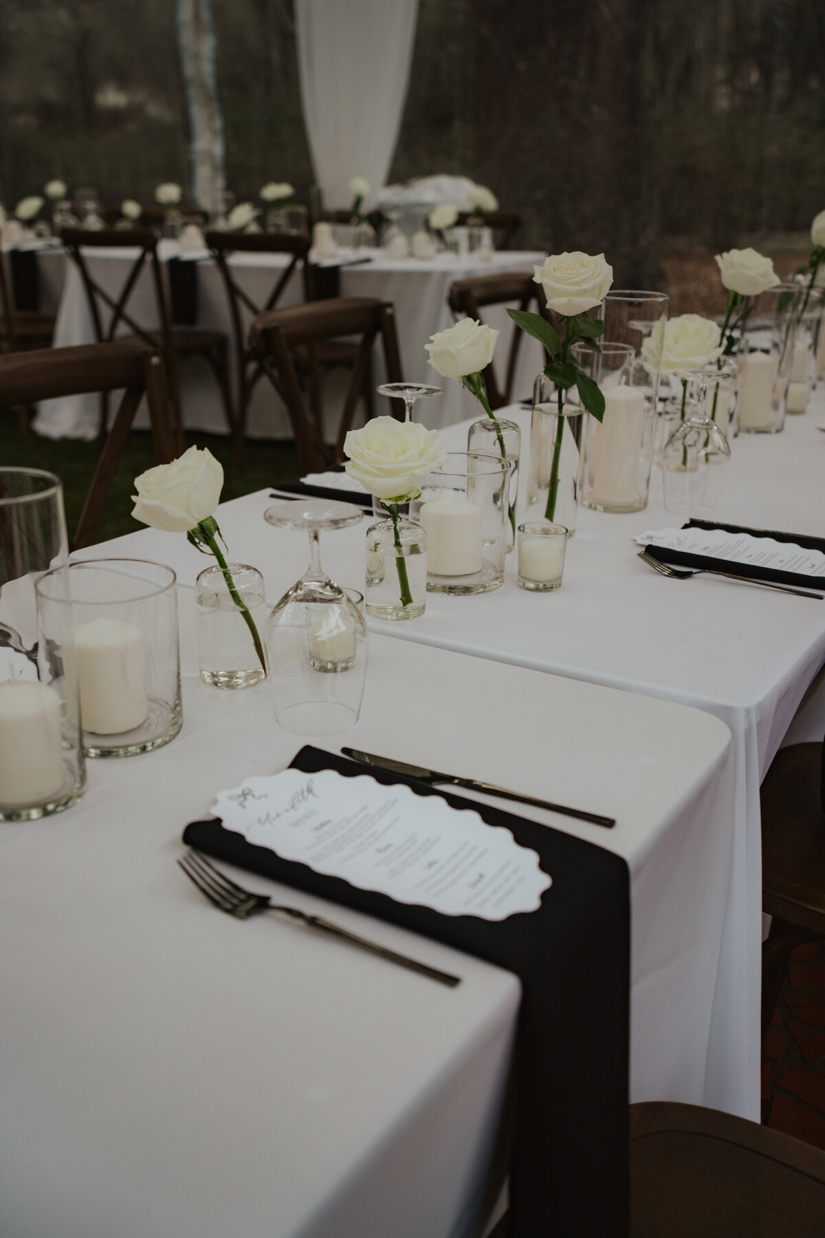 Reception tent with chandeliers and long tables set up beside the estate