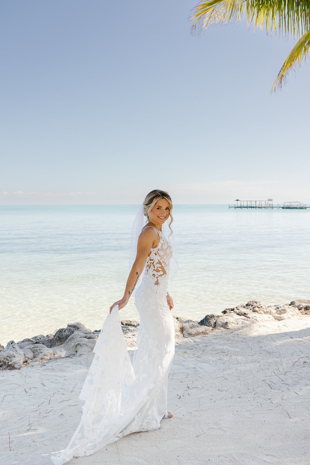Ashley gracefully spins in her wedding dress with the ocean glistening behind her.