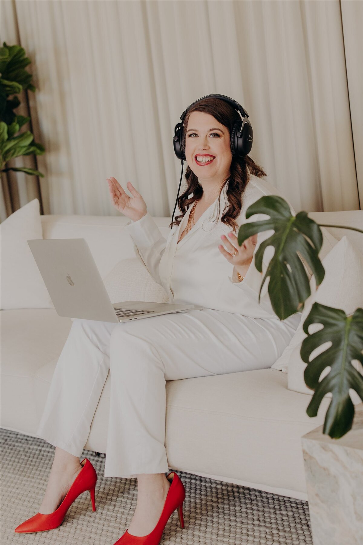 relationship counselor in an all white outfit and black headphones sitting with laptop on lap