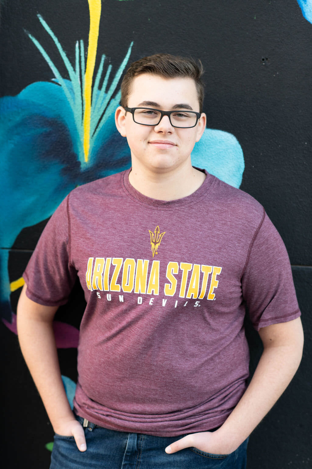 A boy in an Arizona state t-shirt smiling.