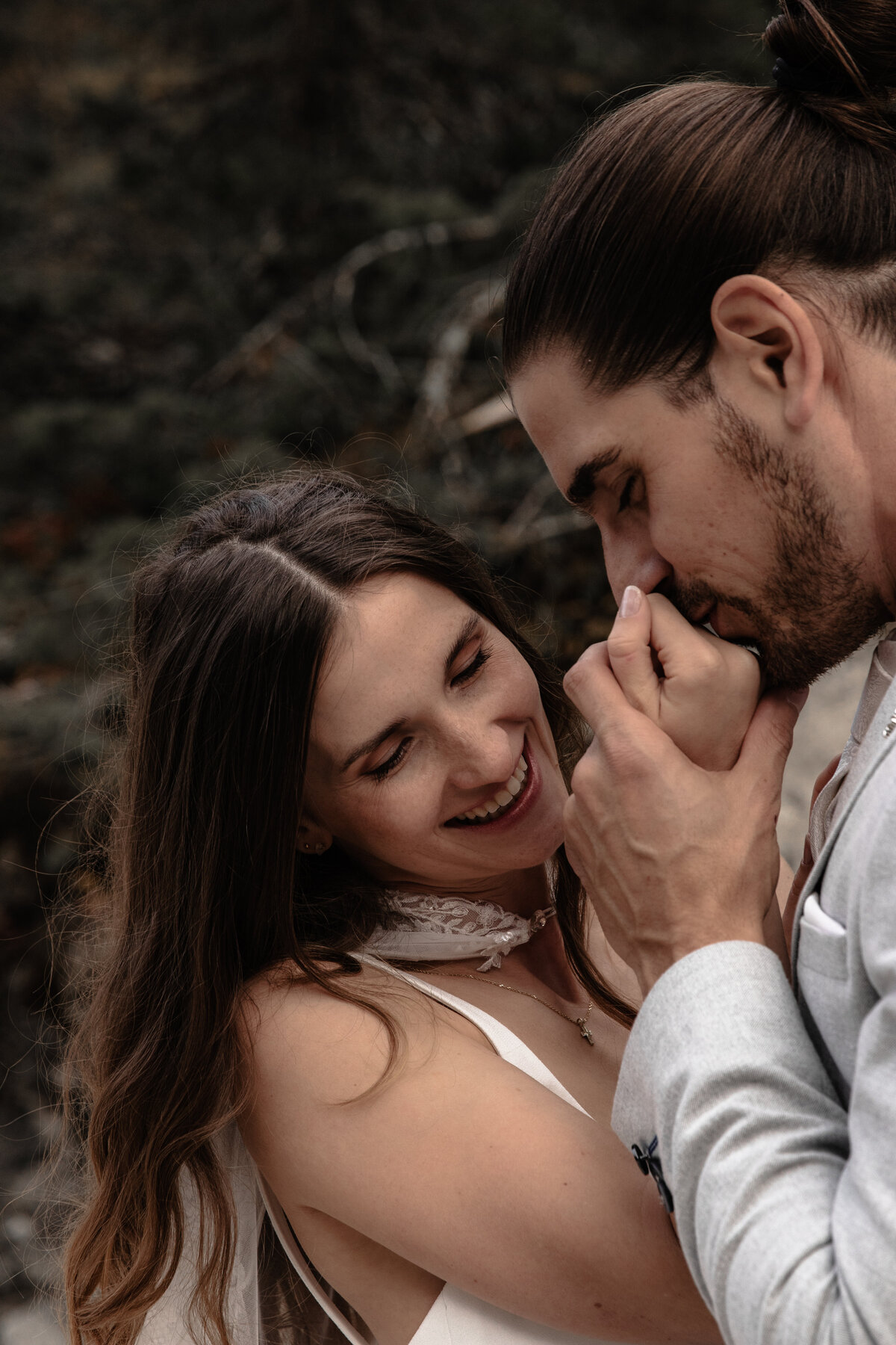 Elopement wedding couple posing on a cliffside with dramatic mountain views
