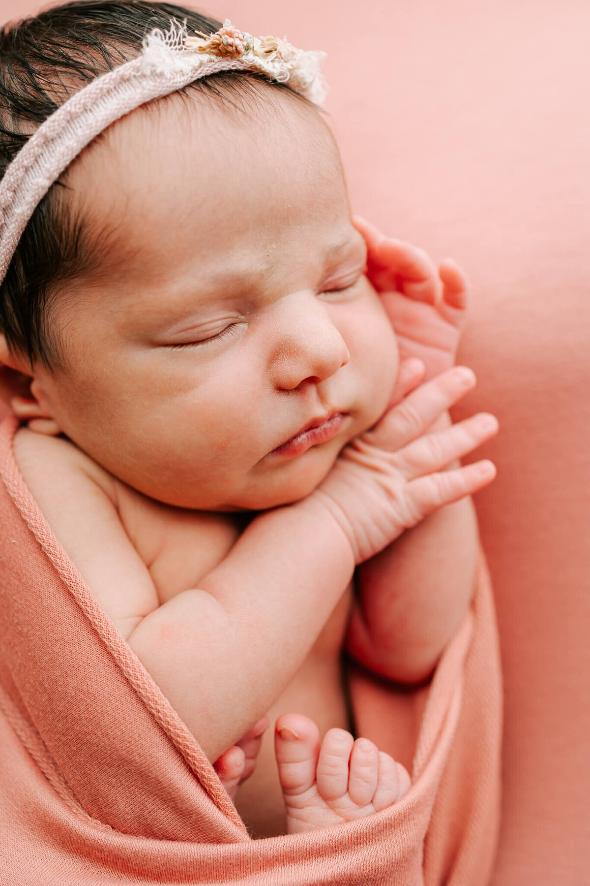 side portrait of newborn girl sleeping on coral colored blanket