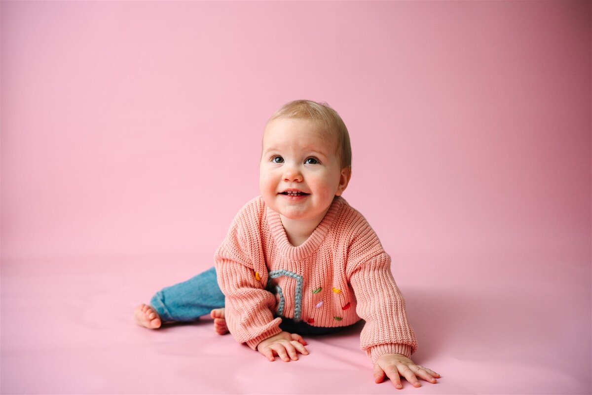 A small baby smiling and crawling on the ground 