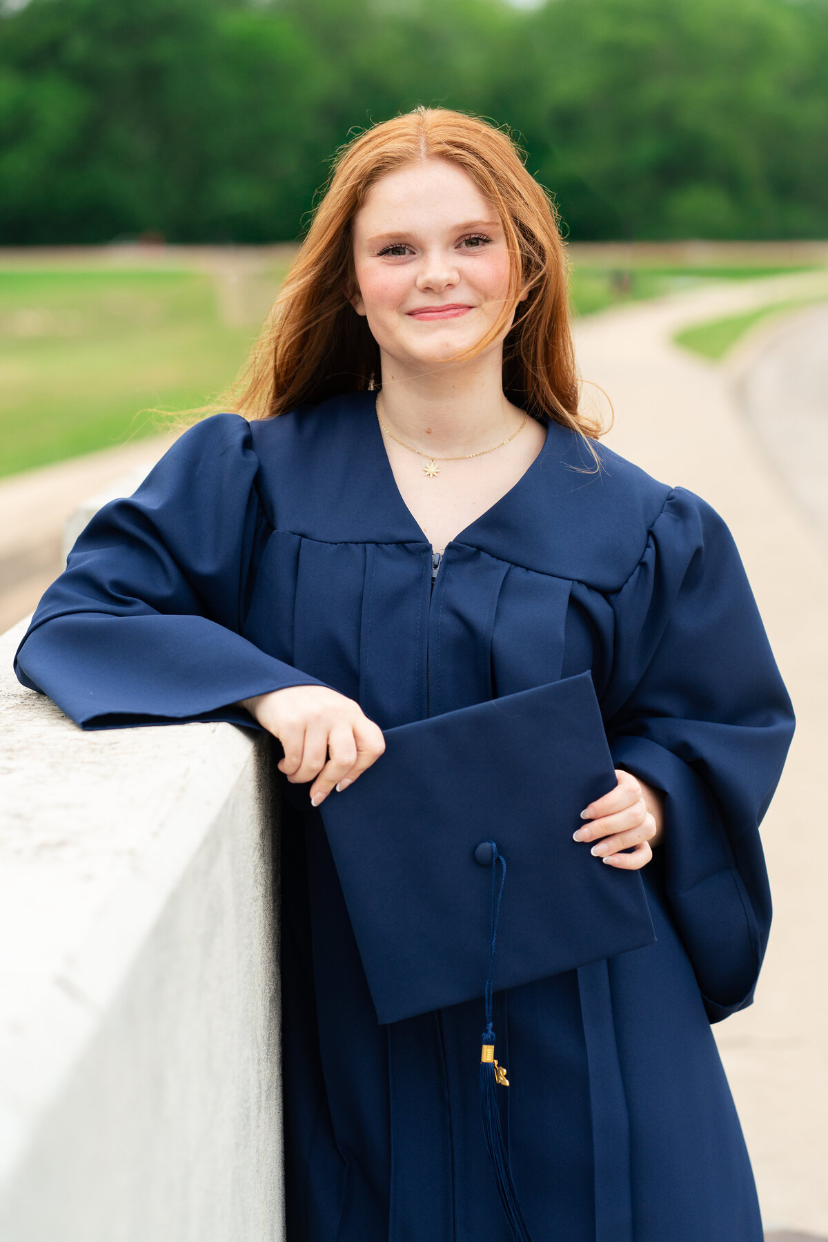 Red head high school senior girl in cap and gown for graduation photos. Austin Senior Graduation.