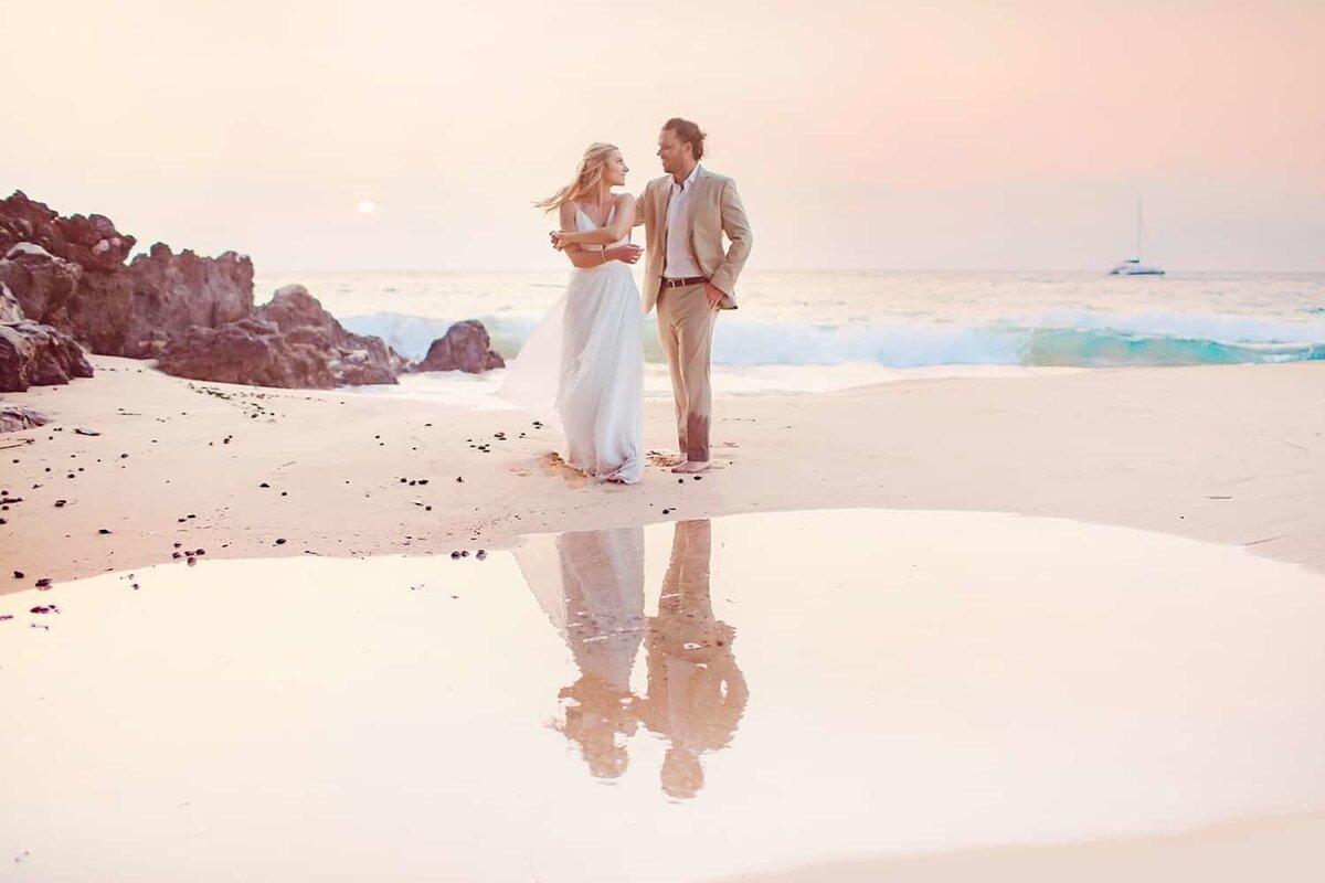 Man twirls his new bride and their reflection is cast in a rockpool during their honeymoon session in Maui with Love + Water