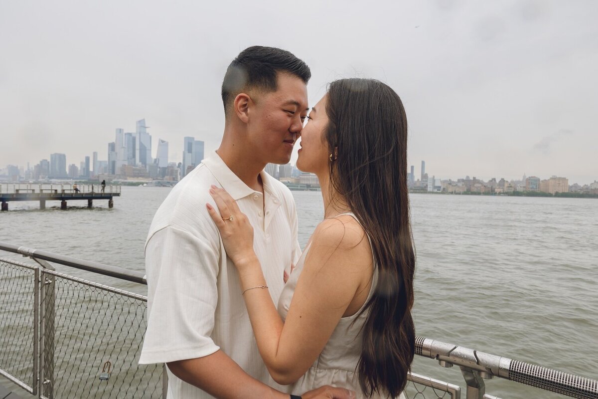Groom-to-be spinning bride-to-be by river with NYC skyline