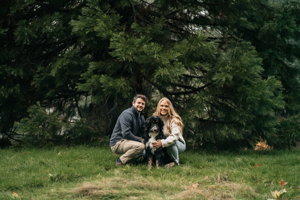 couple in front of tree with their dog