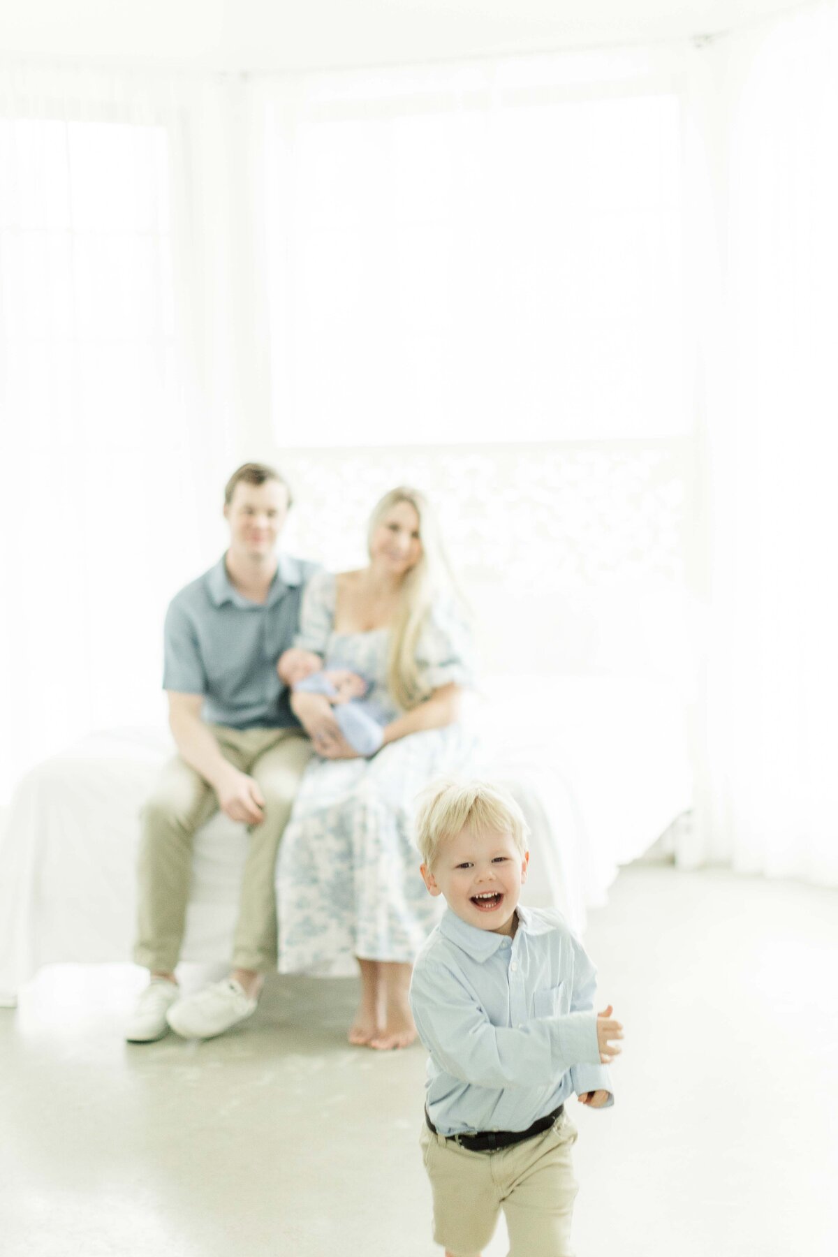 little boy laughs running from family during houston newborn session