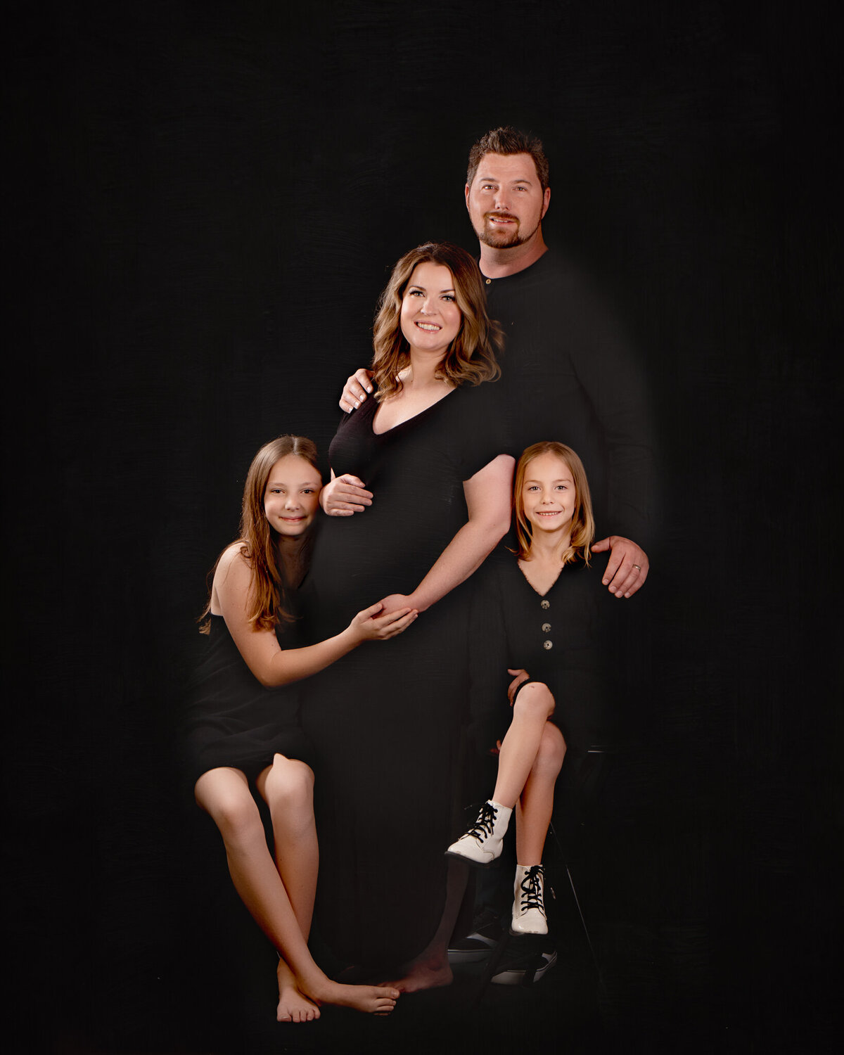 Classic studio family portrait of parents and a young child posed against a black backdrop, captured in Overland Park, Kansas. Perfect for families seeking timeless and intimate photography in the Kansas City area.