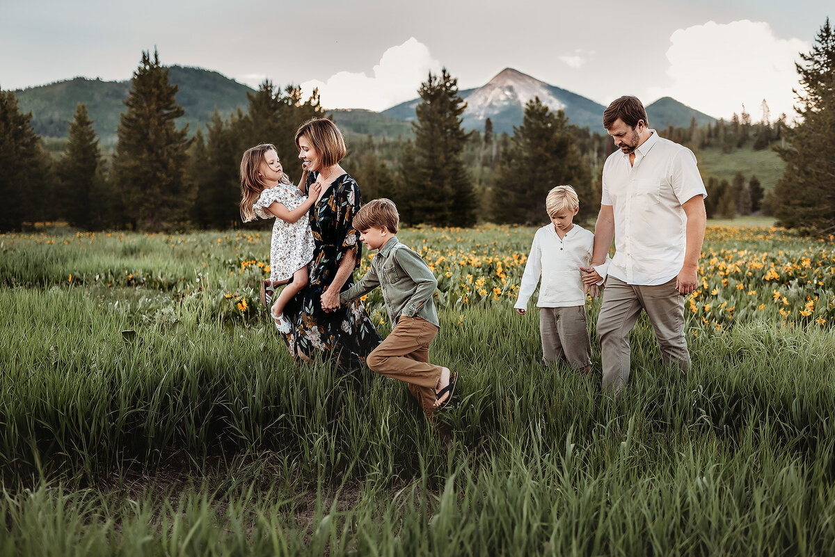 family walking through the grass with mountains in the background