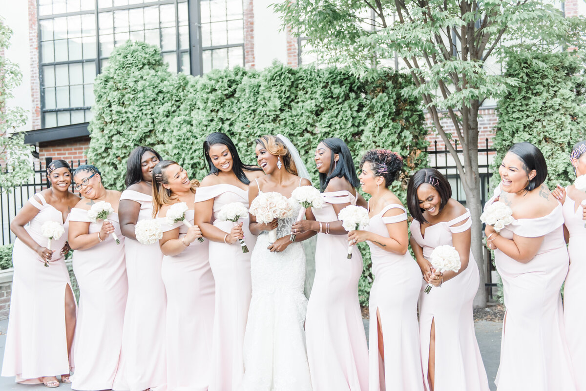bridesmaids in pale pink gowns surround the bride