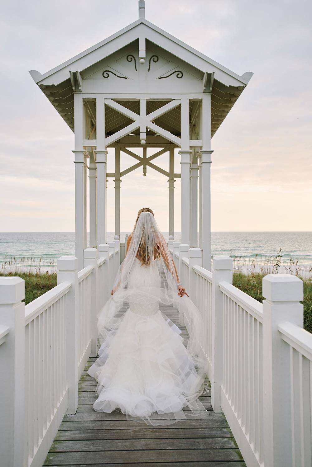 A bride takes her portrait at dusk on a walkover at carillon beach
