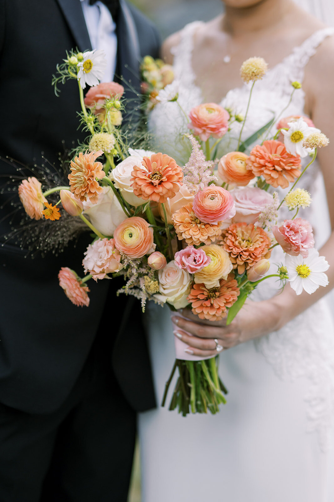 Close up of bride holding a bright, warm floral bouquet