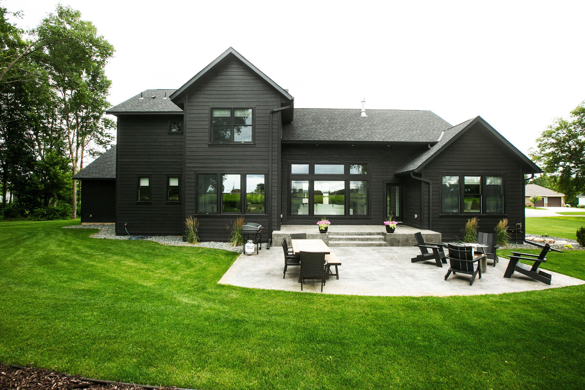 Exterior view of custom home in Otsego, Minnesota with black siding, large patio and windows built by Cornerstone Custom Builds