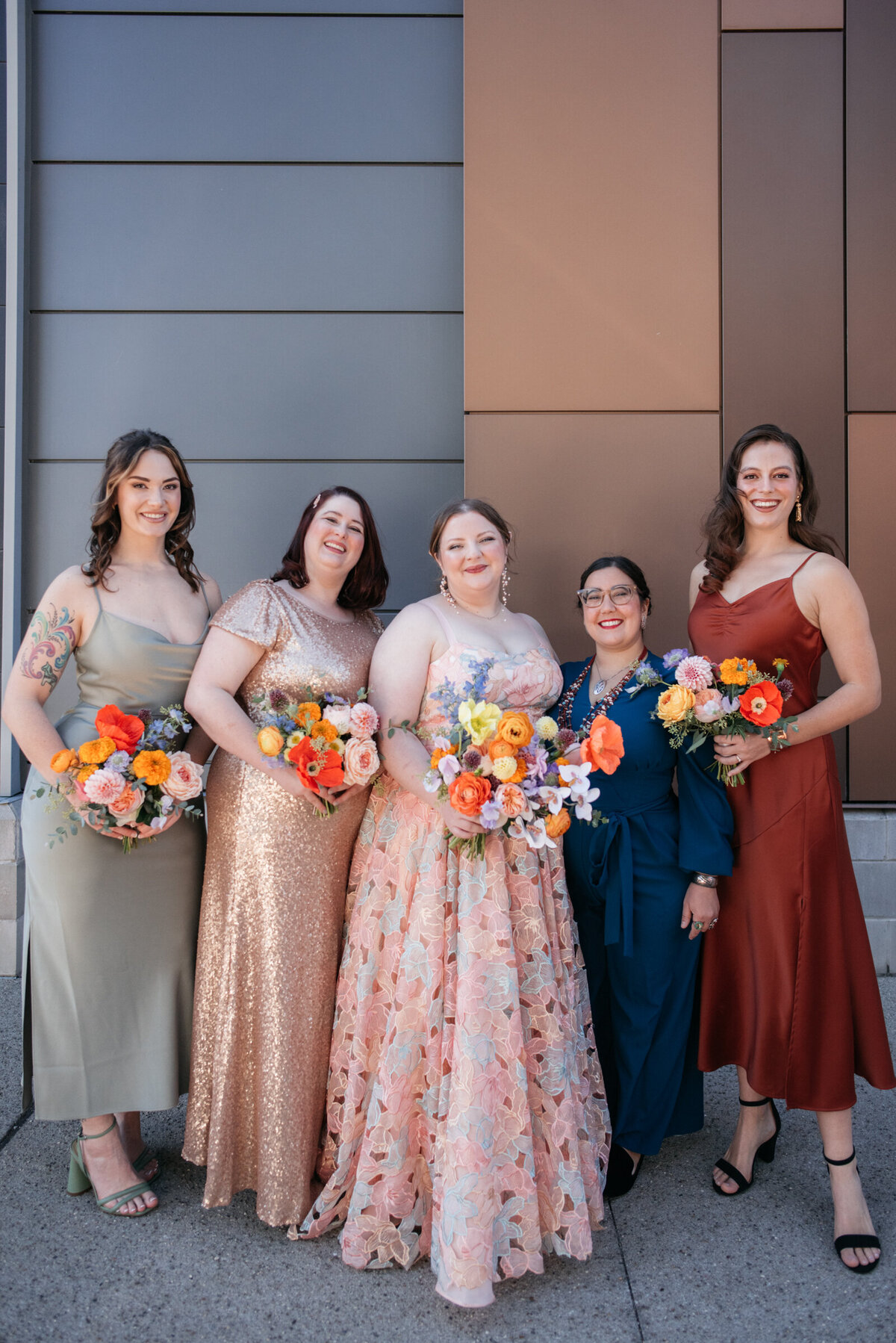 bride wearing colorful wedding dress surrounded by bridesmaids in mismatched colorful bridesmaid dresses