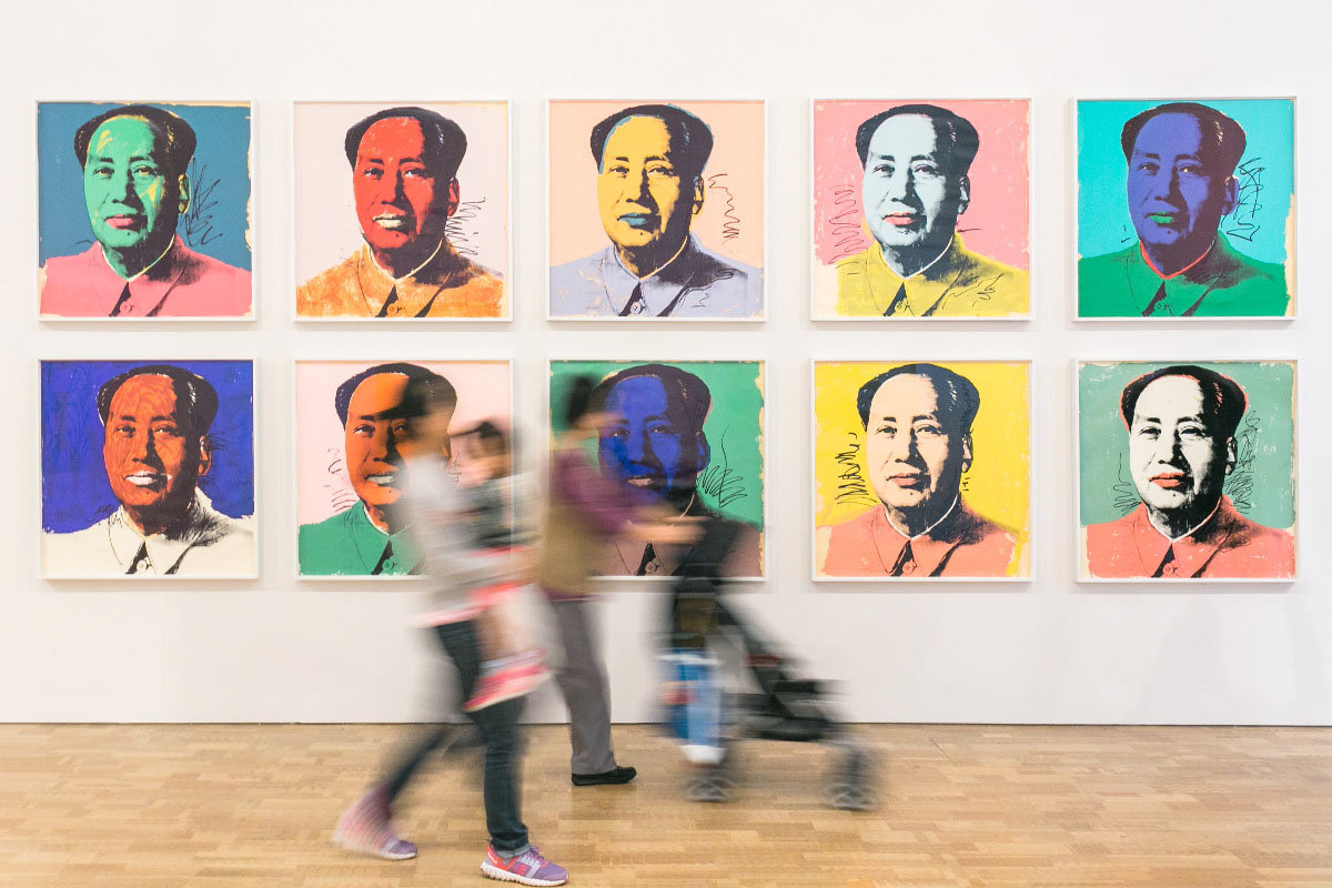 adults with child walking in front of a row of artworks on the wall at an art museum
