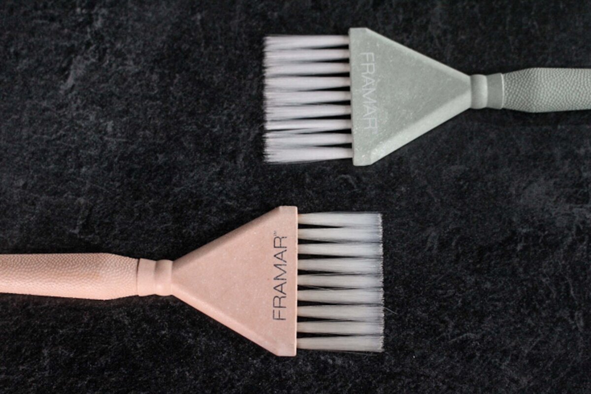 A pink hair color brush facing a  green hair color brush