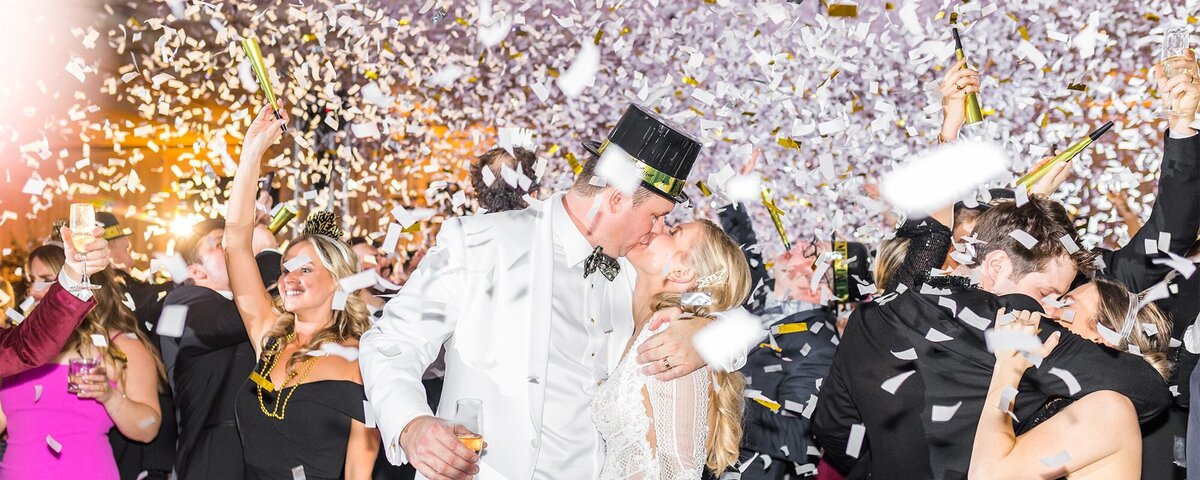 bride and groom kiss at midnight on new year's eve wedding with confetti falling everywhere