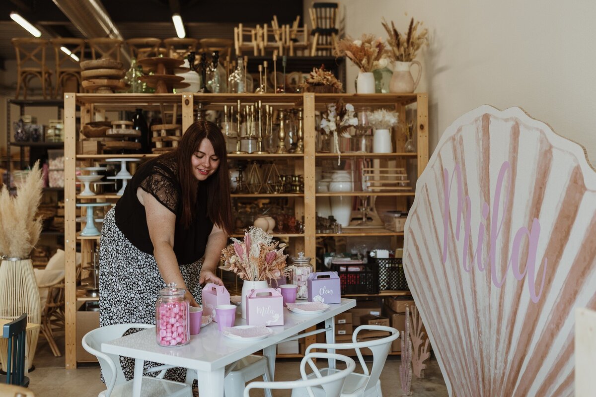 Chloé, la fondatrice de Boum des bambins met en place les derniers détails sur la talbe d'eanniversaire qu'elle a décoré sur un thème sirène dans les tons rose.