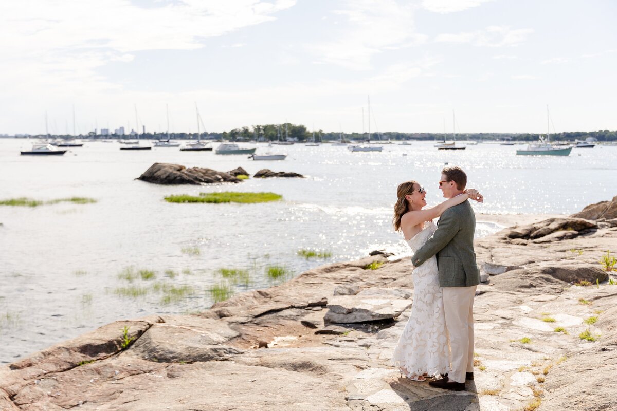 Bride and groom hugging by the water at American Yacht Club in Rye, NY before their rehearsal dinner
