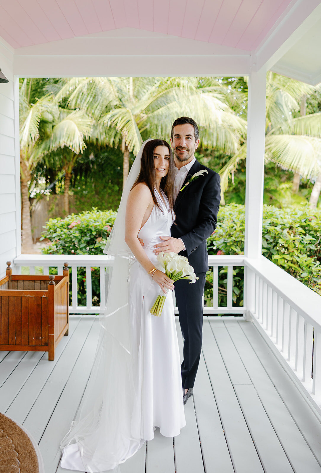 Minette and Evan pose on the porch, radiating love on their wedding day. Florida Keys micro wedding photography by Claudia Amalia.