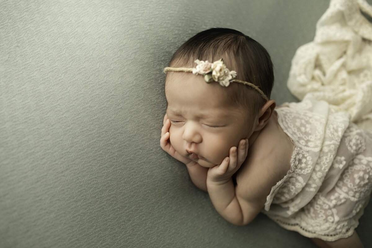 Newborn baby girl wrapped in a soft white swaddle, captured from a side angle as she peacefully sleeps, highlighting her delicate features in a timeless and serene portrait
