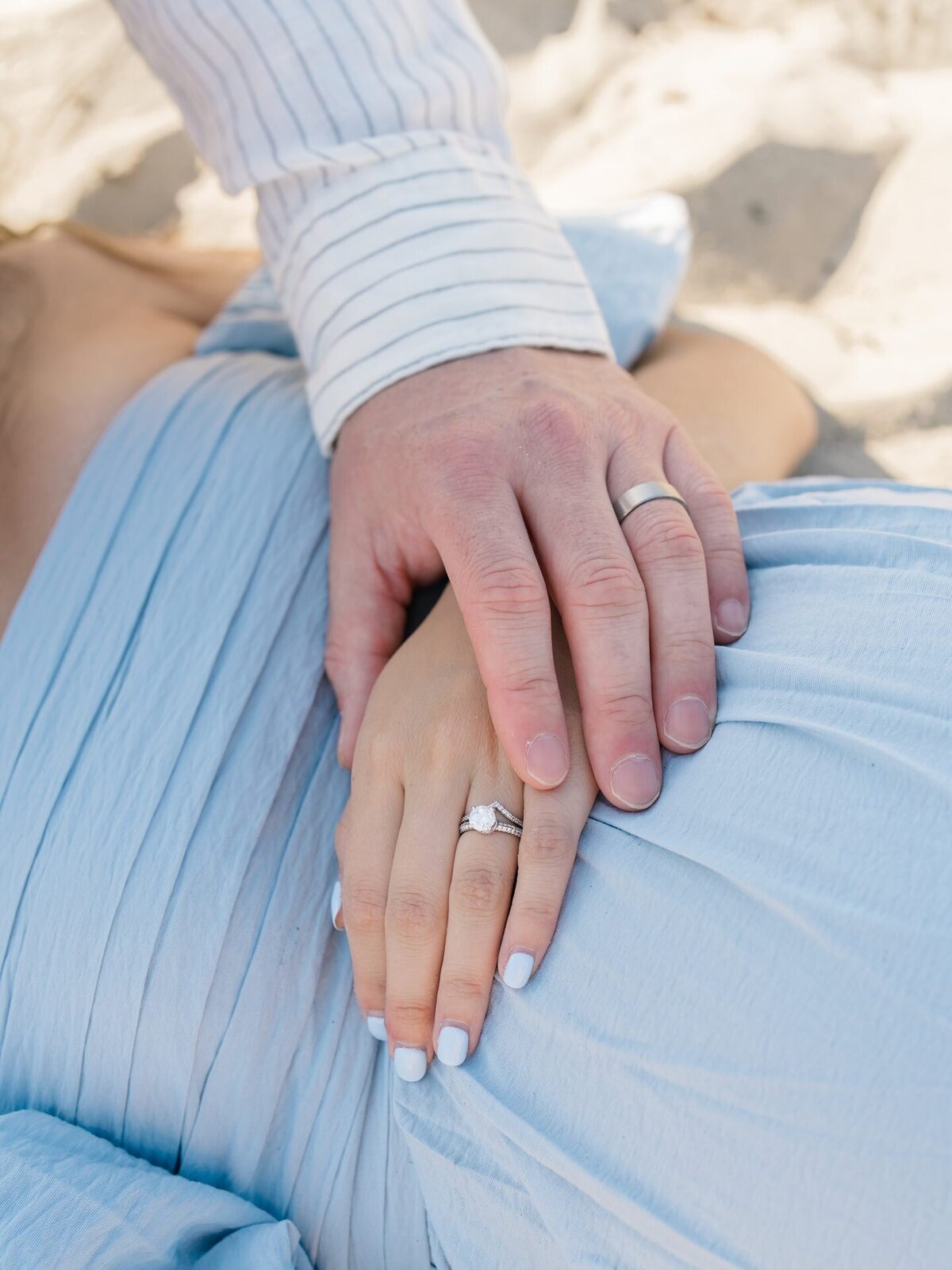 Maternity photo of mom in blue dress and holding husband hand