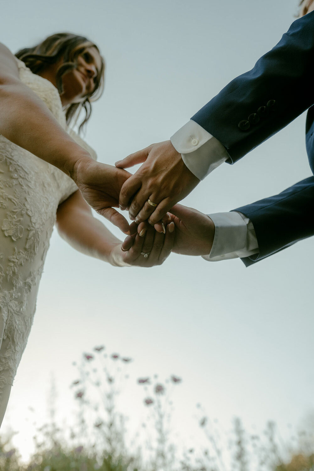 Bride and groom holding hands, close-up from below