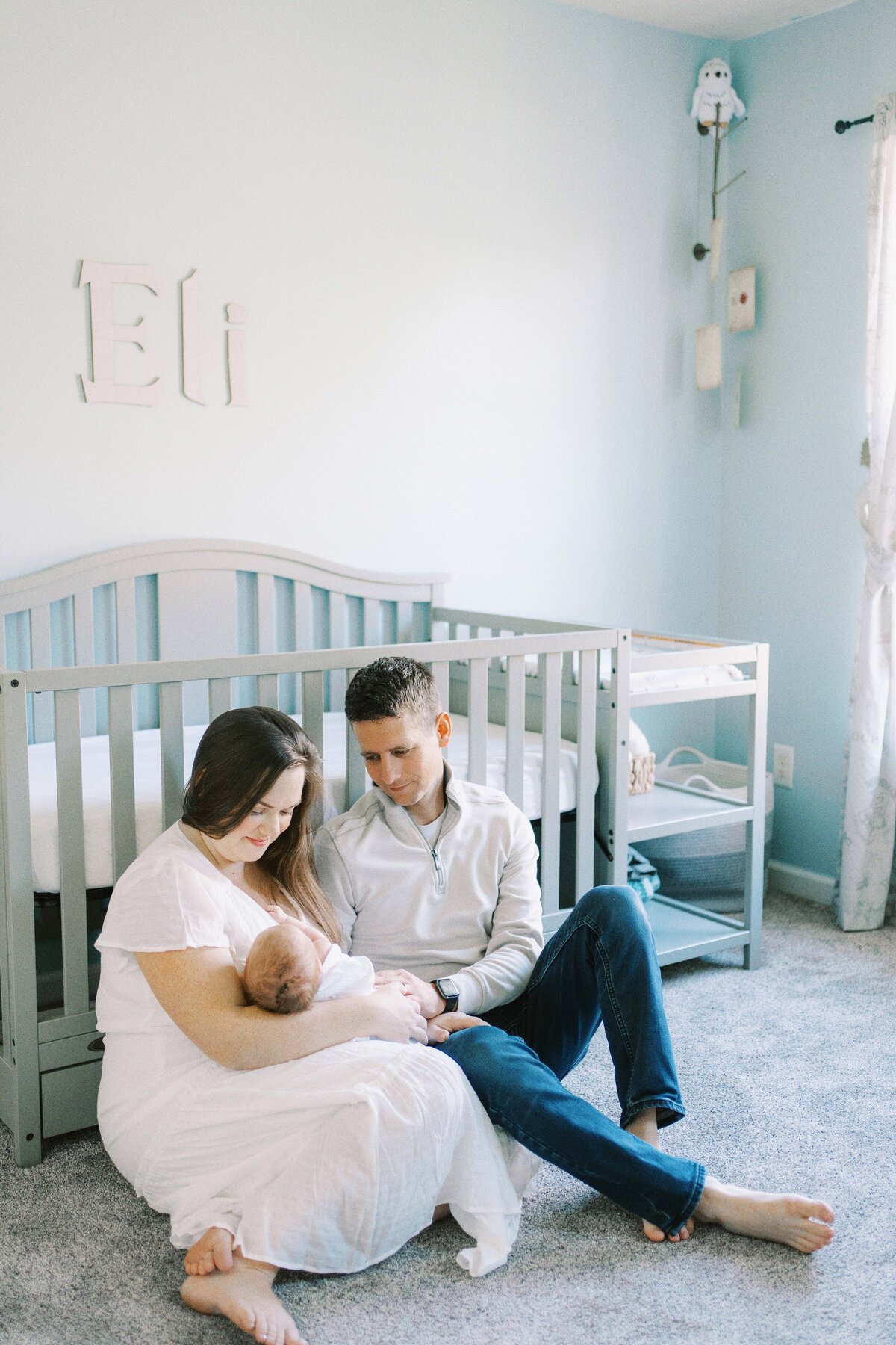 mom and dad sitting in nursery room floor gazing at baby