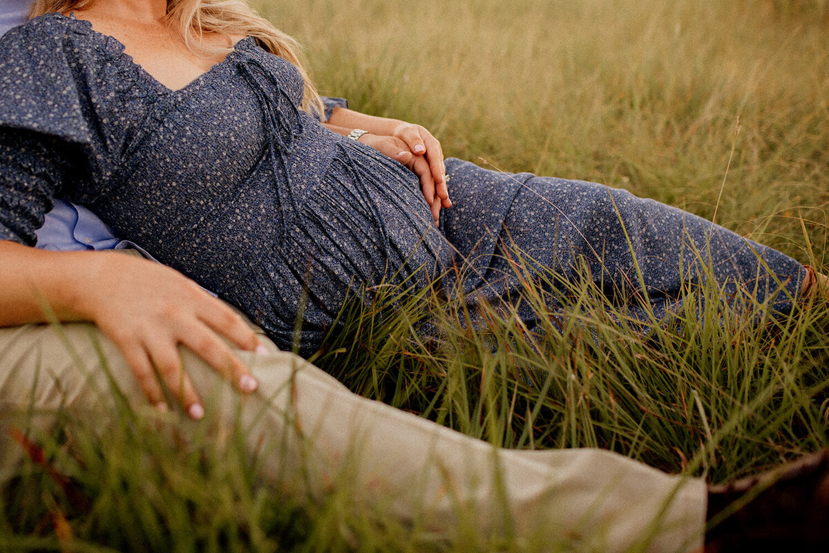 Maternity photo of a pregnant couple lying together in a field, photographed by San Antonio family photographer Sara James.