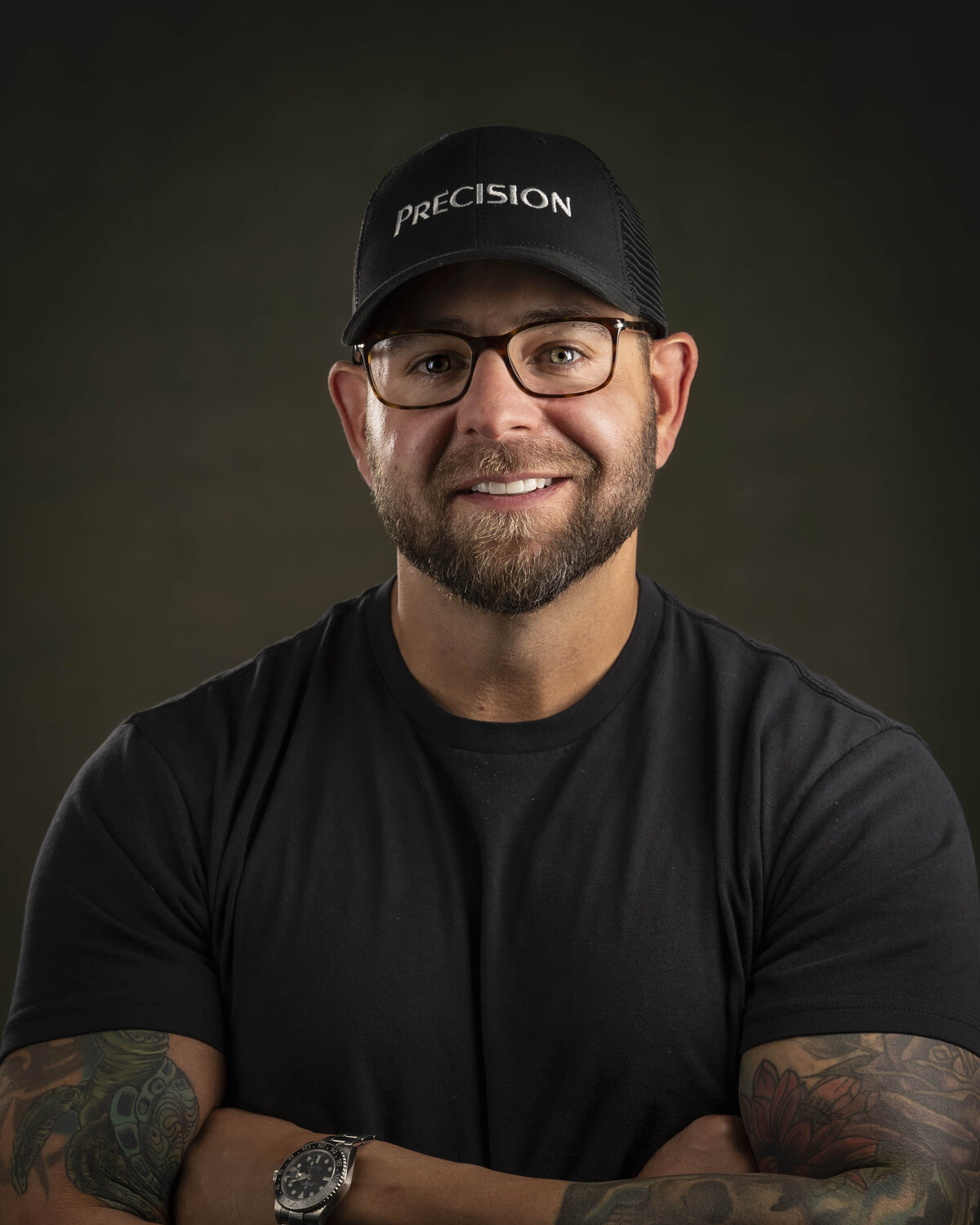 Headshot in MA of smiling man in black t-shirt, glasses, and beard, posed against dark studio backdrop by Rob Faber Photography.
