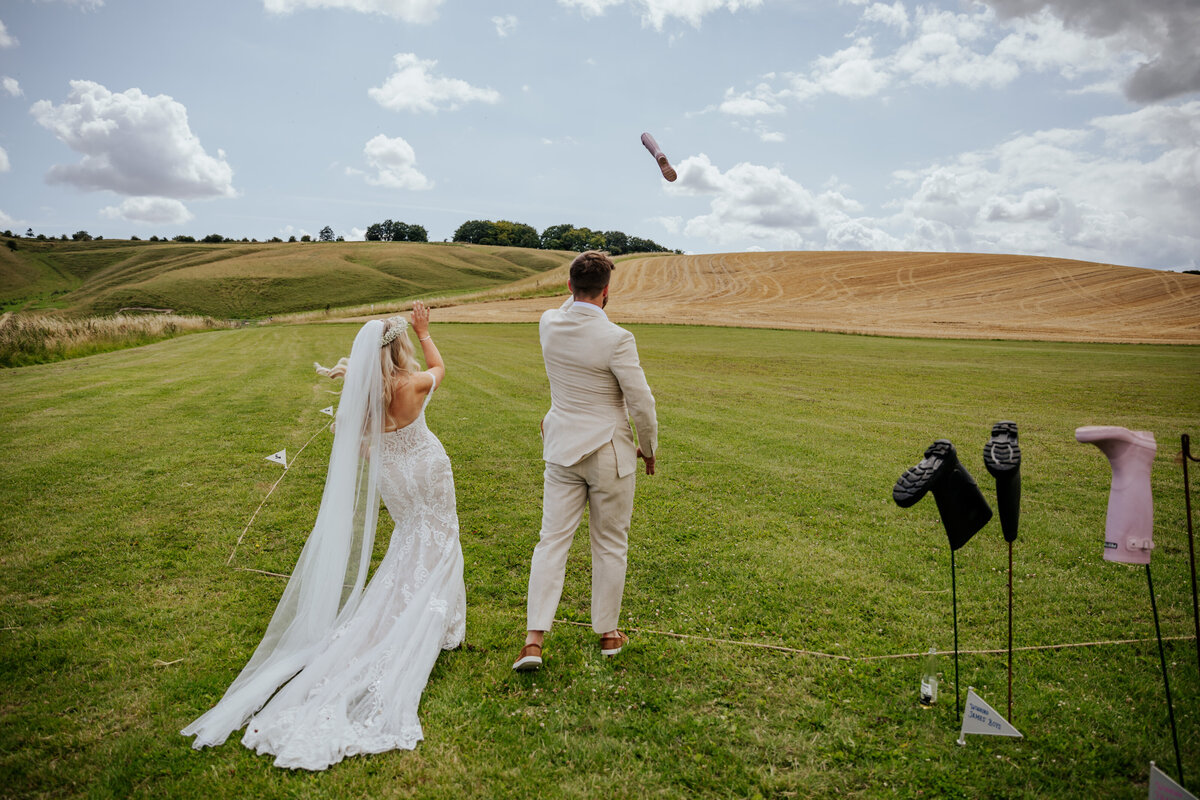 Bride and groom 'welly wanging' in the fields at Wellington Barn