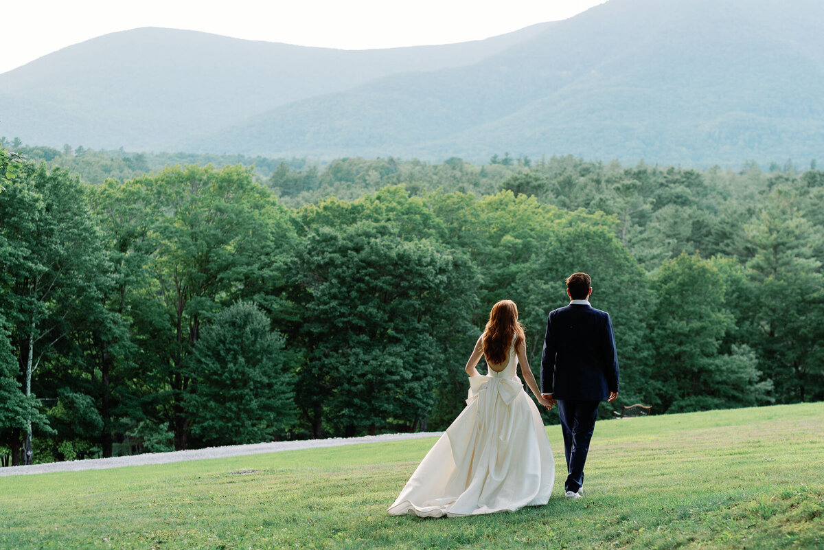 bride and groom at wilburton inn walk towards mountains in sareh nouri gown