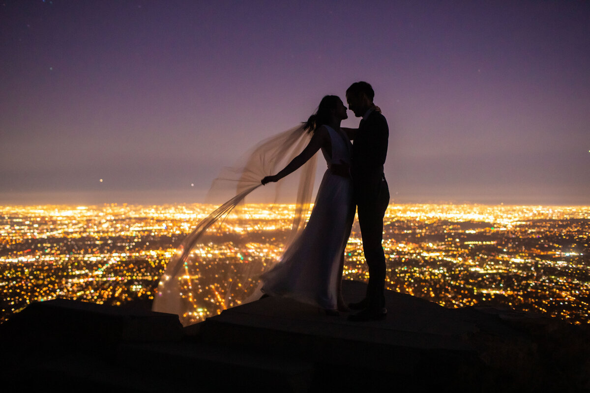 Bride and groom with city lights in background