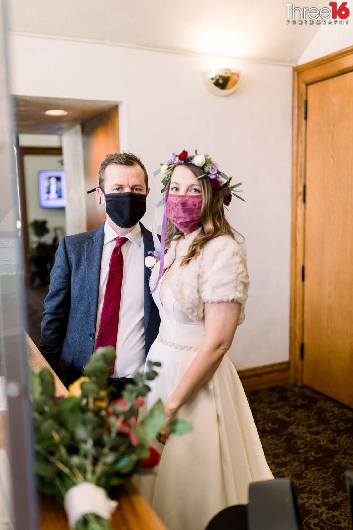 Bride and Groom to be wait at an office wearing Covid masks for their elopement ceremony to begin